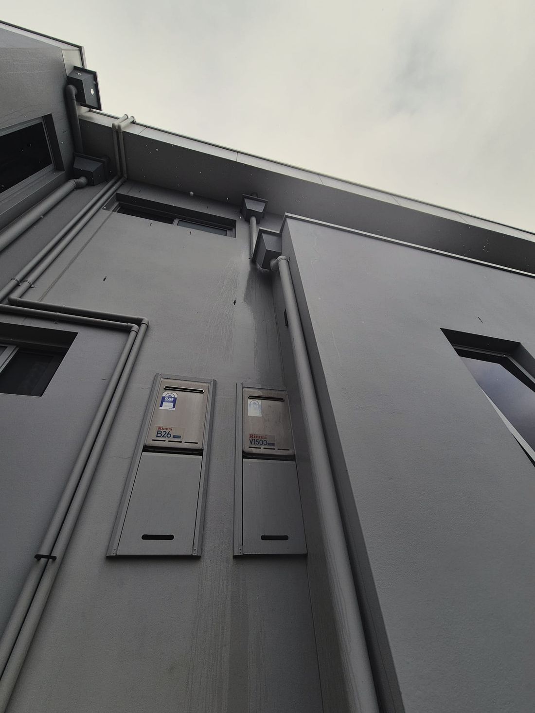 A grey rendered facade painted through around downpipes